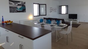 Une cuisine moderne avec des meubles blancs, un plan de travail en bois et un coin repas comprenant une table blanche dressée pour quatre personnes.