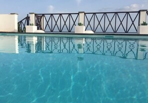 A swimming pool with clear blue water, surrounded by a white wall and a black metal fence. - modern villa with stunning sea views and private pool (Macher)
