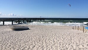 A beach with a boat, a pier, and a clear sky. - generous thatched cottage (160 m²) on the Baltic Sea, sauna, stove, forest edge location (Rerik)