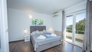 Une chambre à coucher avec un lit, des tables de chevet, une fenêtre avec des rideaux et une vue sur le balcon.