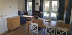 A compact kitchen with a wooden table, white chairs, a blue sofa, and a built-in oven. - Salland Vakantie Heeten (Heeten)