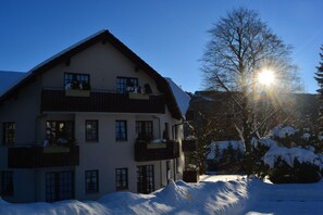 A multi-story building with balconies, surrounded by snow-covered trees and a clear sky. - Hoffmann's apartment in the residence Bocksbergblick (Goslar)