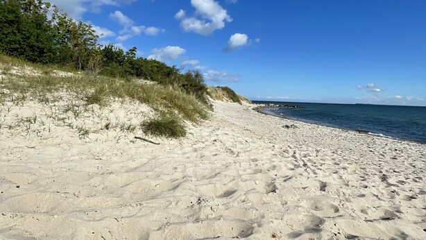 En sandstrand med en klar himmel och några moln.