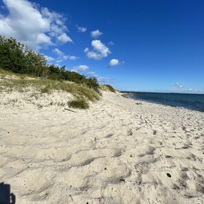 A sandy beach with a clear sky and some clouds.