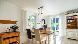 En matplats med ett träbord, stolar, ett vinställ och en bokhylla.