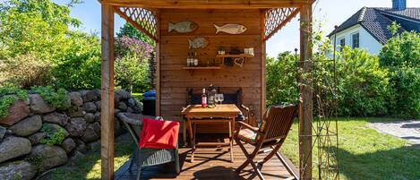 Un espacio de descanso al aire libre con mesa, sillas y un pérgola.