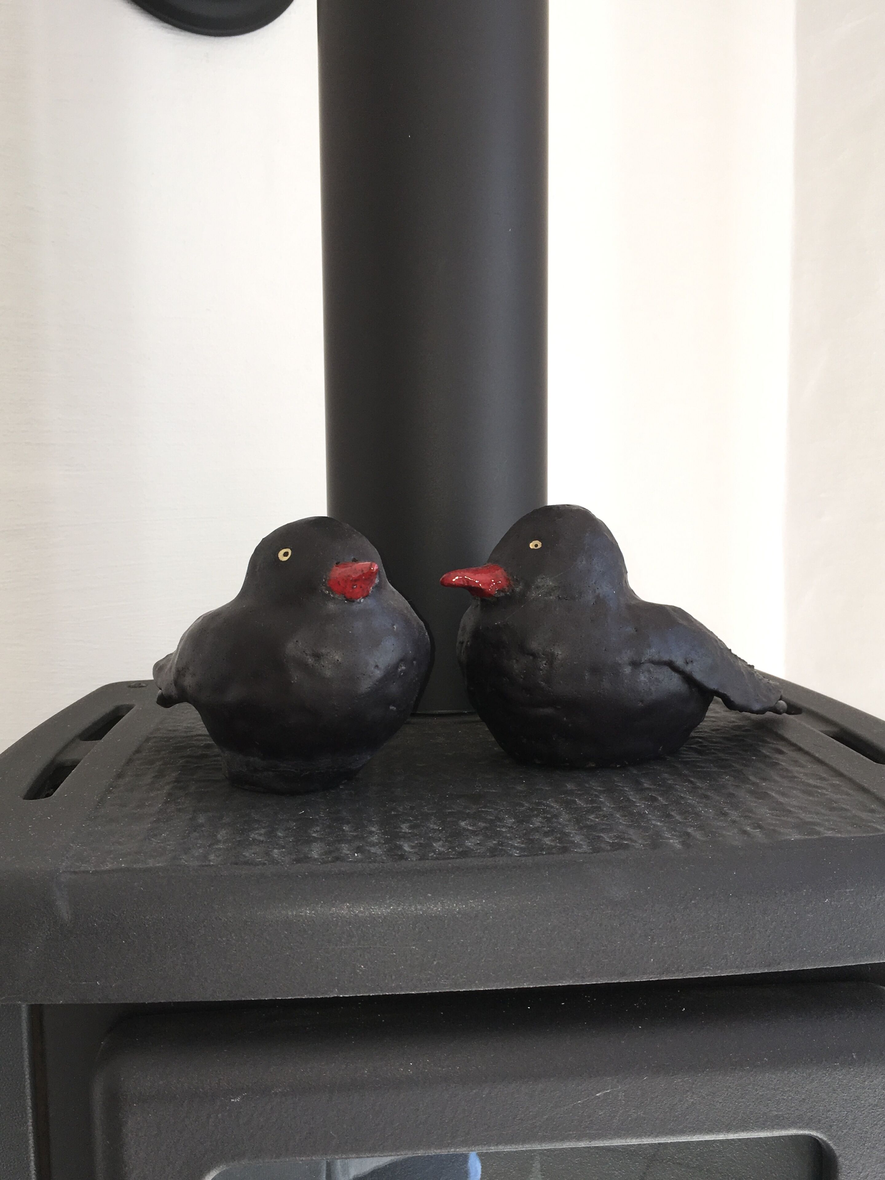 Dos figuritas de pájaros negros sobre una estufa negra.