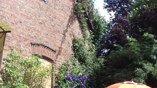 A brick building with a window, a brick pathway, and a grassy area.