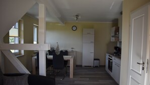 A compact kitchen with a dining area, a white refrigerator, and a clock on the wall.