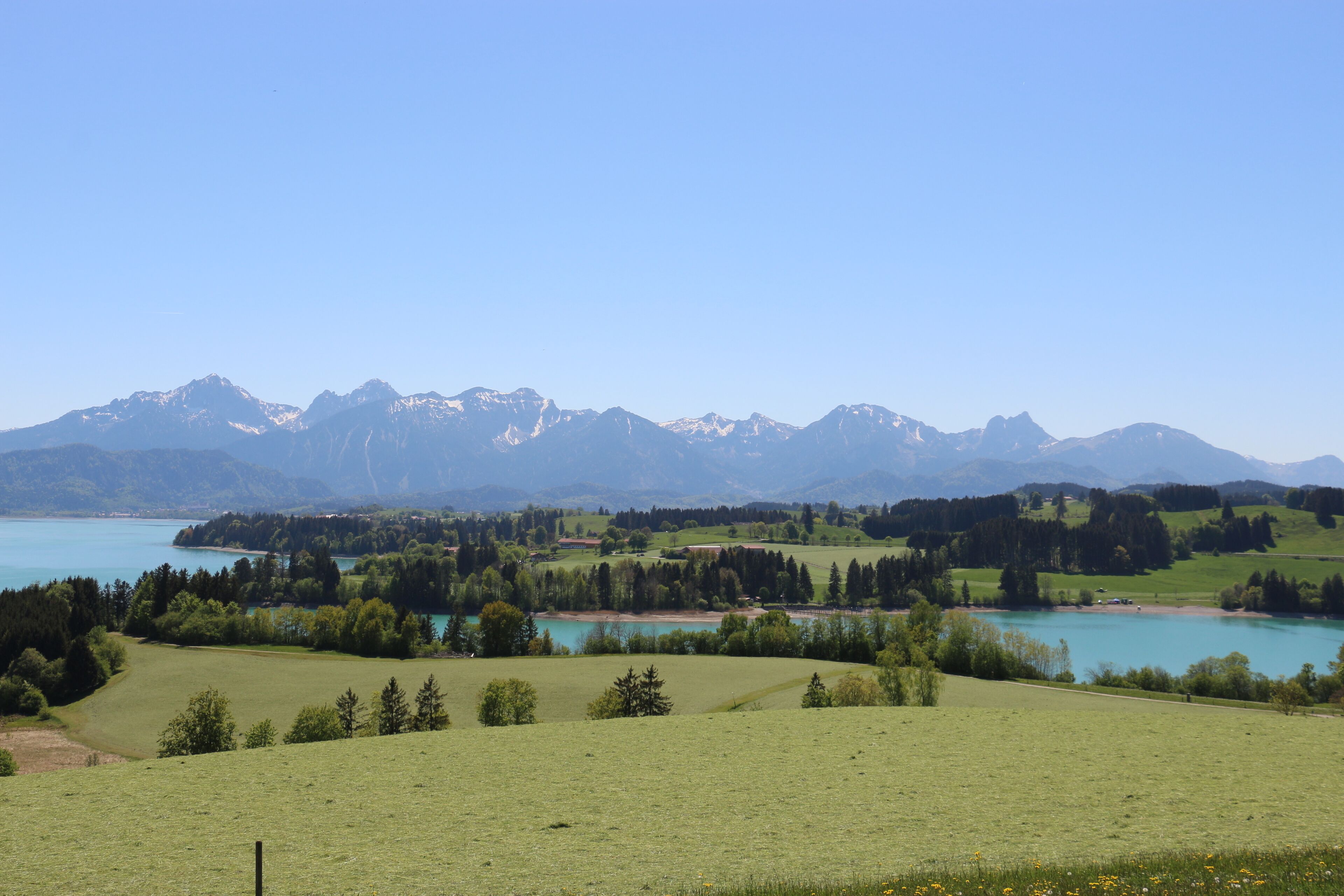 A panoramic view of a mountainous landscape with a lake and green fields.