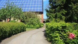 A gravel path leading to a building with a solar panel array. - Charming family and pet friendly apartment in rural idyll - pure relaxation (Kiel Pries)