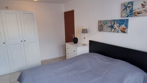 Un dormitorio con cama, cómoda, armario y una lámpara en el techo.