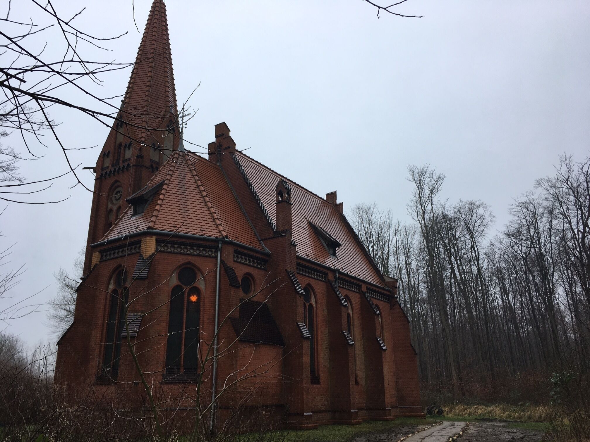 A brick church with a tall steeple and arched windows.