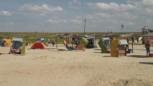 Una playa con varias cabañas de playa coloridas y una tienda roja.