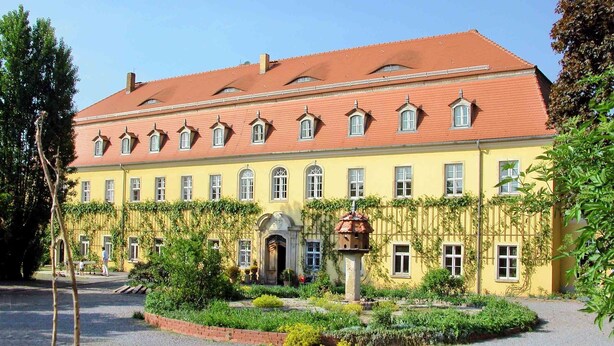 A yellow building with a red roof, multiple windows, and a garden in front. - Very large (105m2) family-friendly apartment in castle 'Rittergut Heyda' (Lossatal)
