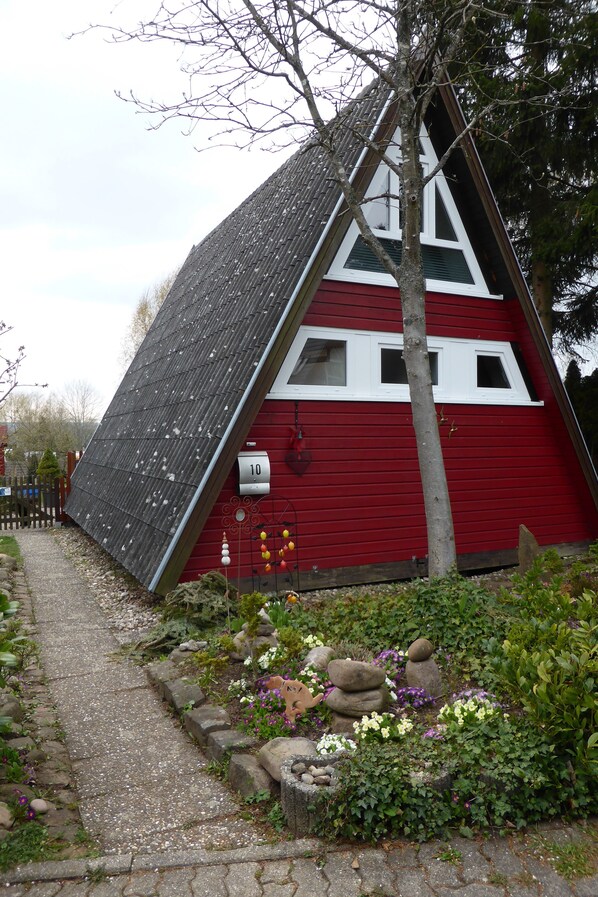 A red house with a sloped roof, a mailbox, and a stone pathway leading to it. - Nurdach holiday home in the Black Forest (Neuhausen)
