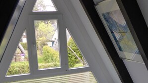 Un dormitorio en ático triangular con tragaluz, una cama y vistas al exterior.