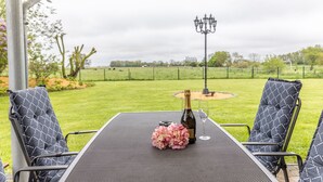 Eine Terrasse im Freien mit einem Tisch für zwei Personen, komplett mit einer Champagnerflasche und einem Glas.