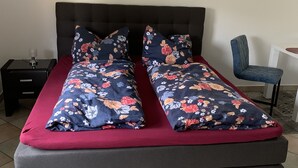 A double bed with floral bedding, a dark headboard, and a bedside table with a lamp.