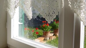Ein Fenster mit weißen Vorhängen und Blick auf Pflanzgefäße draußen.