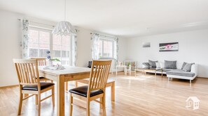 A spacious living area with a wooden dining table, two chairs, a sofa, and a coffee table. - Cozy vacation apartment in Bierdorf am Ammersee  (Dießen am Ammersee)