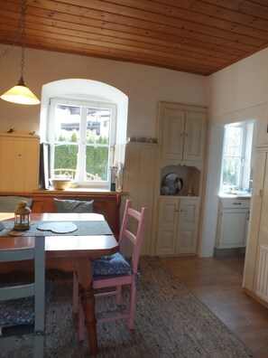 A cozy kitchen with wooden cabinets, a dining table with chairs, and a window providing a view of the outside.