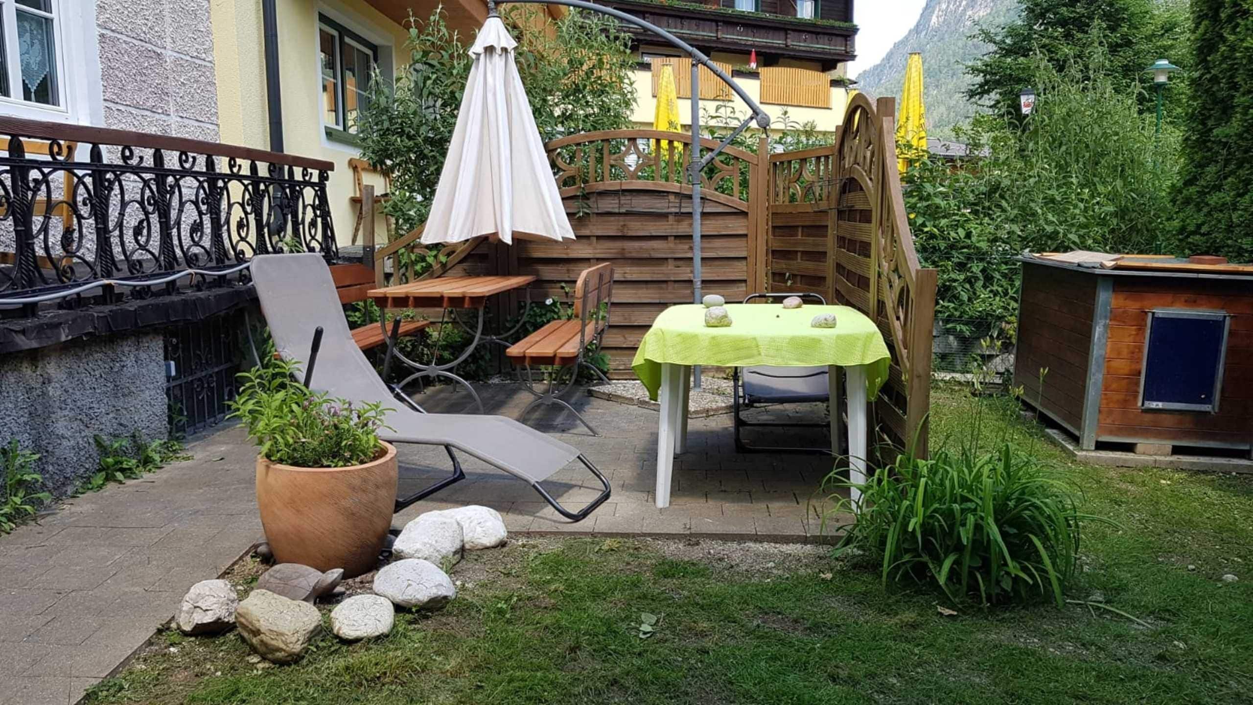Eine Terrasse mit Tisch und Stühlen, einem Blumentopf und einem Holzzaun.