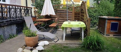 Eine Terrasse mit Tisch und Stühlen, einem Blumentopf und einem Holzzaun.