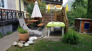 A patio with a table and chairs, a potted plant, and a wooden fence.