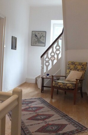 A staircase with a decorative railing, a patterned rug, and a floral armchair. - Holiday home - Müllers Holiday Salzburgerland (Niederland)