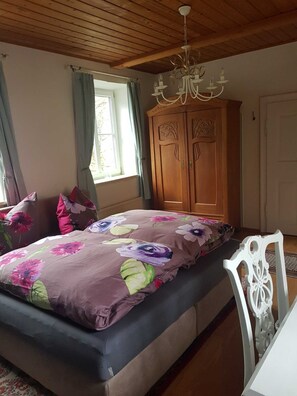 Une chambre à coucher avec un lit, une armoire en bois et un lustre.