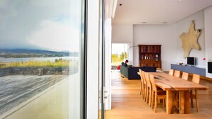 Ein modernes Interieur mit einem großen Glasfenster, einem Holztisch und einem aufgehängten Tierfell an der Wand.