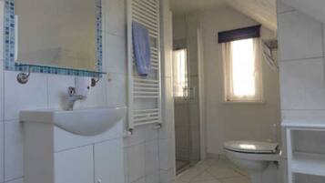 A bathroom with a sink, toilet, and shower area.