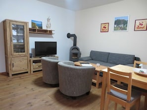 Una sala de estar con televisor, sofá, aparador de madera y chimenea.