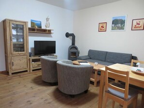 Una sala de estar con televisor, sofá, aparador de madera y chimenea.