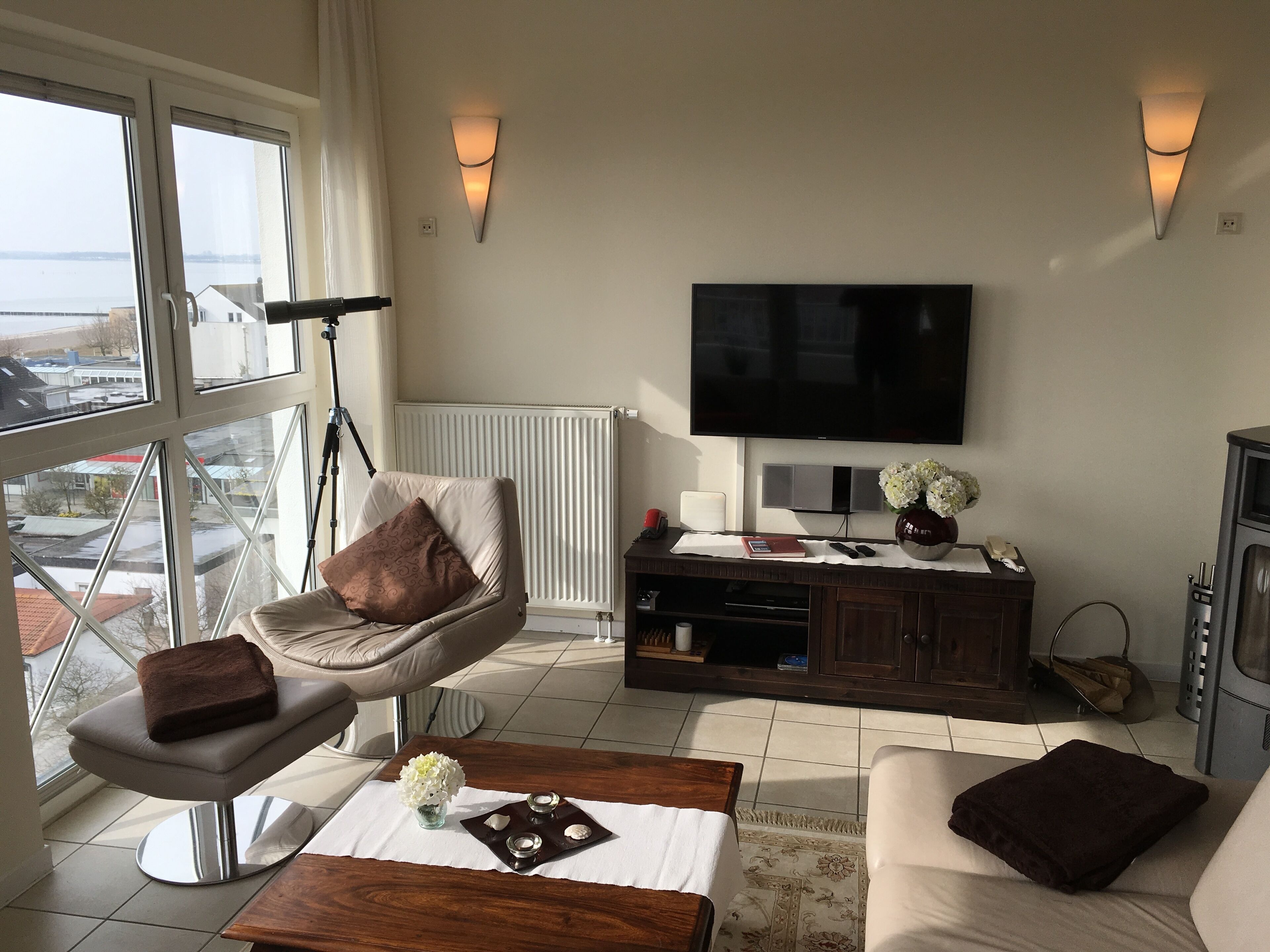 Ein Wohnzimmer mit einer Couch, einem Sessel, einem Couchtisch, einem Fernseher und einer Heizung.