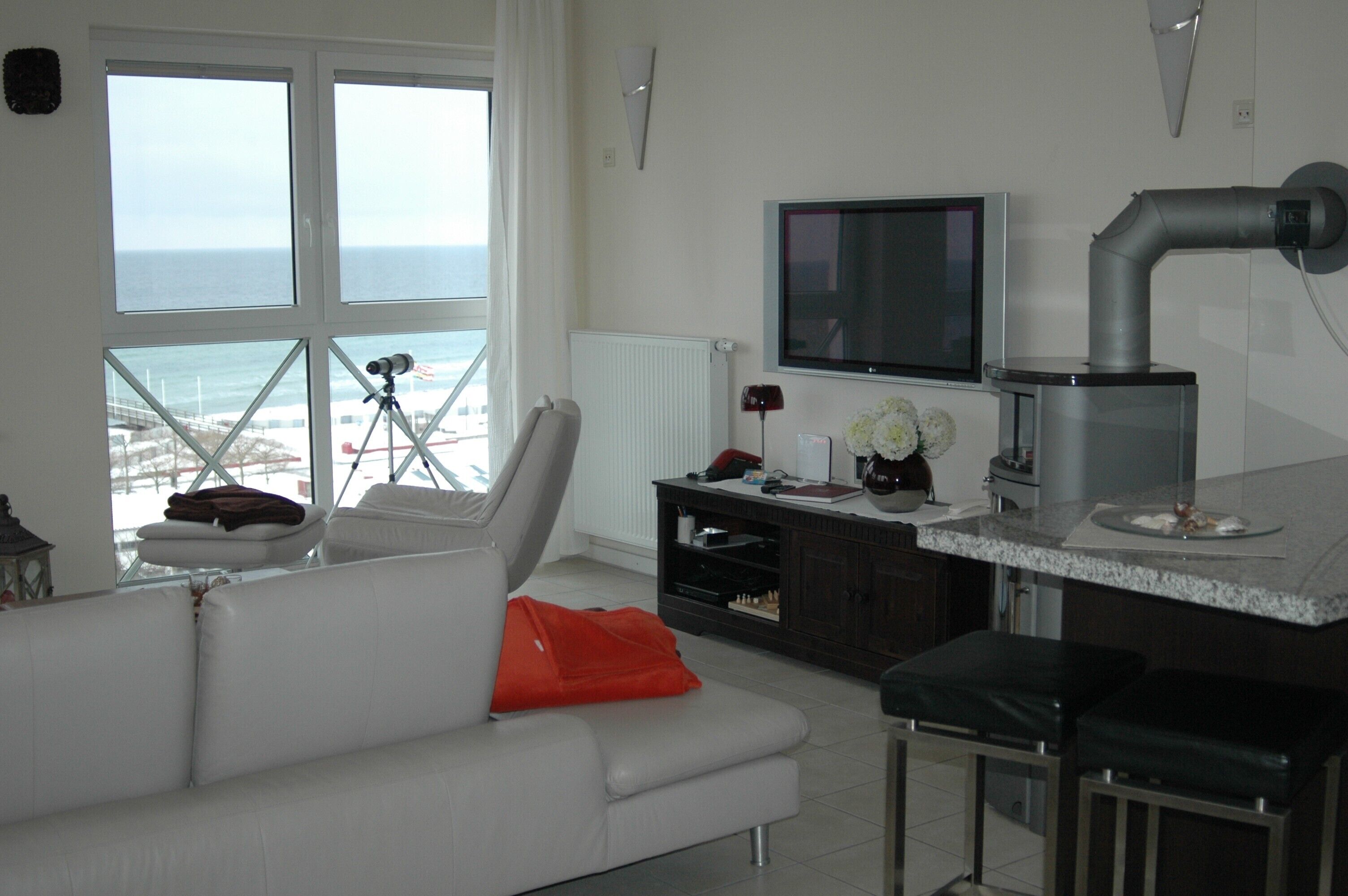 A modern kitchen with a large window, a TV, and a view of the ocean.