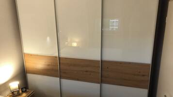 Una habitación con cama, una mesita de noche con lámpara y un armario corredero con panel de madera.