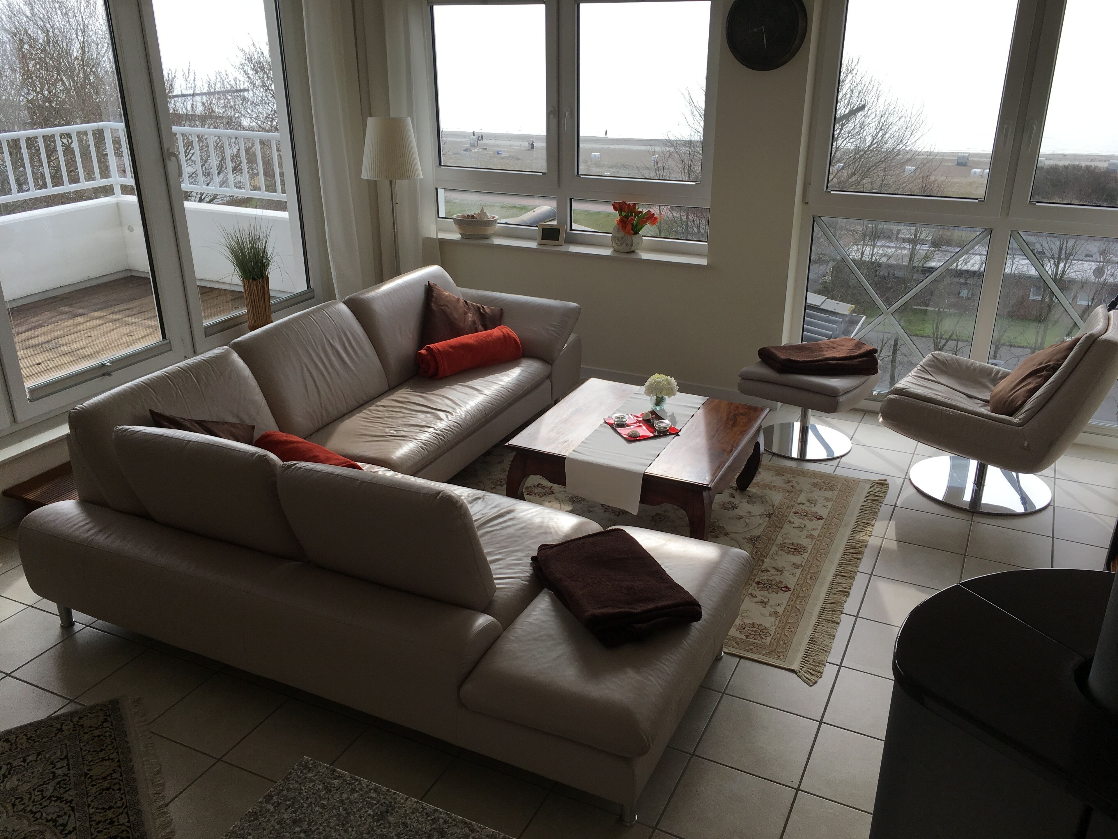 En moderne stue med sofa, sofabord og en lænestol. Store vinduer med udsigt udad.