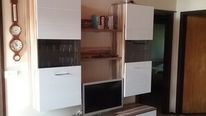 A modern living room with a built-in TV, white cabinets, and a wooden coffee table. - Vacation home bungalow, one floor, fenced garden, dog allowed, 2 parking spaces (Butjadingen)