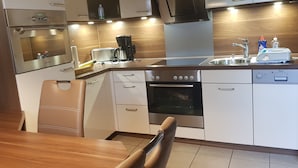 A modern kitchen with stainless steel appliances, a built-in oven, and a dishwasher. - Vacation home bungalow, one floor, fenced garden, dog allowed, 2 parking spaces (Butjadingen)
