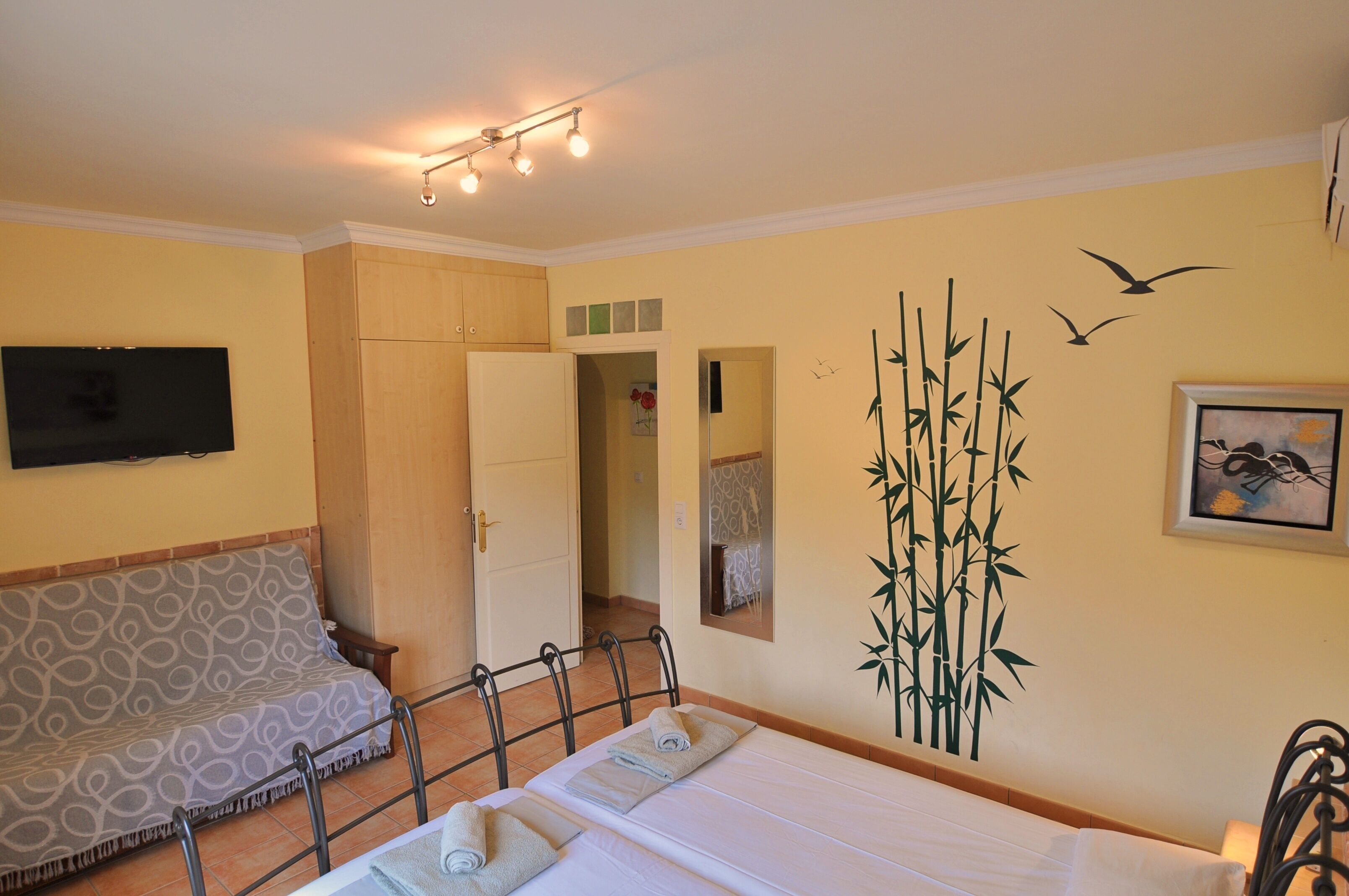 A hotel room with a bed, a sofa, a television, and a mirror.