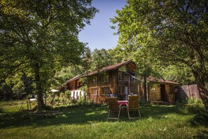 Eine rustikale Holzhütte mit rotem Dach, umgeben von üppigem Grün und Bäumen.