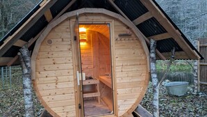 A wooden cabin with a circular entrance, a wooden staircase inside, and a metal bucket outside. - Family-friendly holiday home in the most beautiful hiking area!  (Arnbruck)