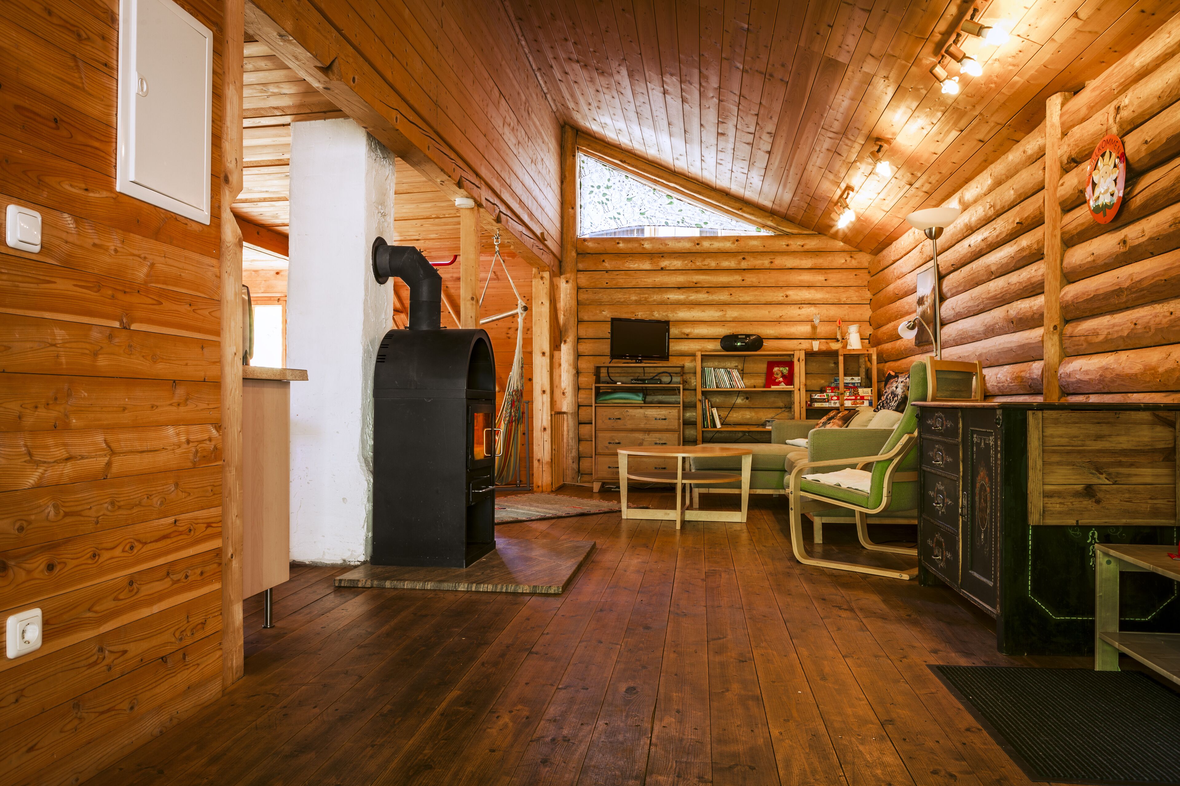 A log cabin interior with a fireplace, wooden walls, a television, and a dining area. - Family-friendly holiday home in the most beautiful hiking area!  (Arnbruck)