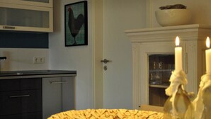 Une cuisine équipée d’un four à micro-ondes, d’un tableau représentant un coq encadré, d’une porte et d’un meuble contenant une bougie.