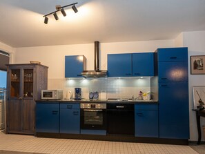 A modern kitchen with blue cabinets, a microwave, an oven, and a coffee maker.