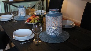 Une table à manger dressée avec des assiettes, des verres et une lanterne décorative.