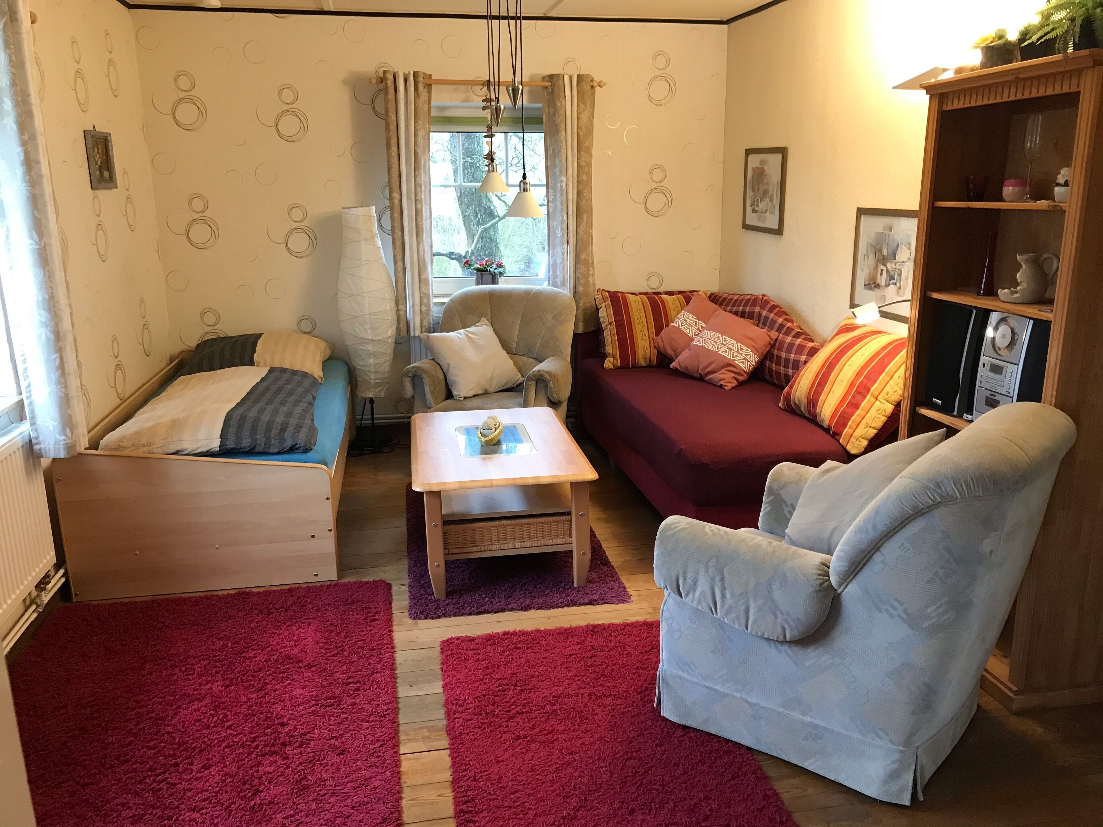 Un espacio habitable compacto con cama, sofá, sillón y una mesita.