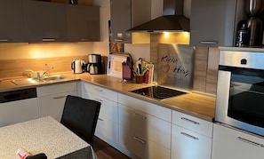 Eine moderne Küche mit Einbauofen, Kaffeemaschine und einem Schild mit der Aufschrift 'Die Küche ist das Herz des Hauses'.